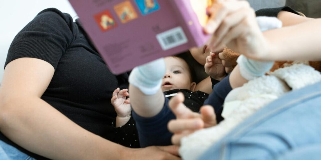 A baby and family reading together, promoting love and education. Cozy indoors setting.